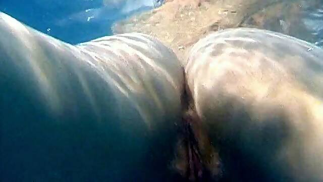 Skinny dipping teens play in the pool and finger underwater